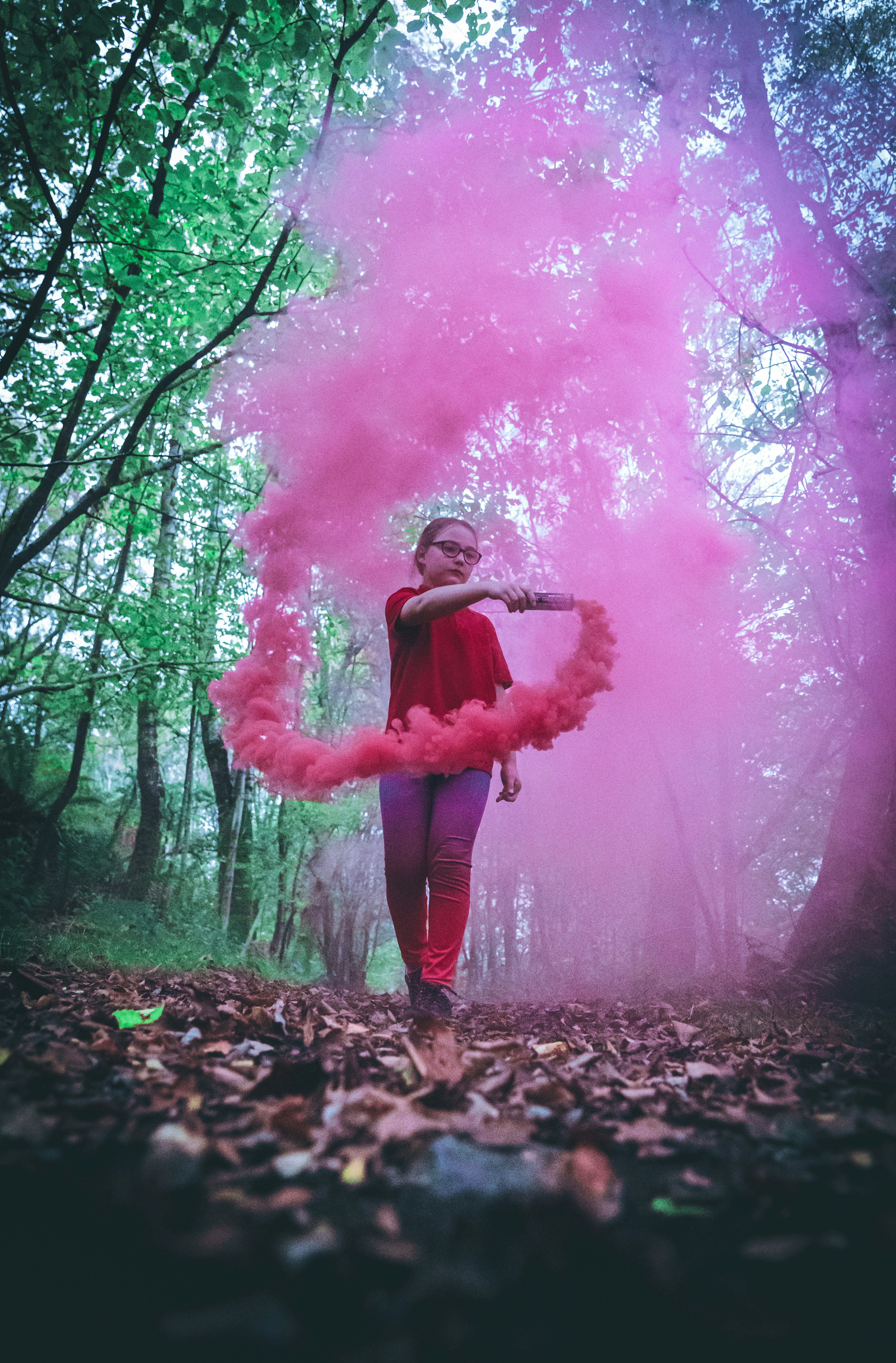 woman in pink long sleeve shirt standing on brown dried leaves covered ground